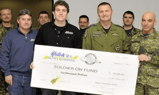 a group of men standing next to each other holding a large check